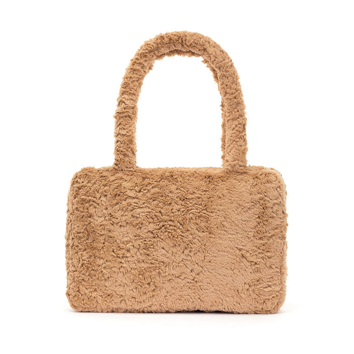 Teddy bear-shaped handbag with a face on a white background