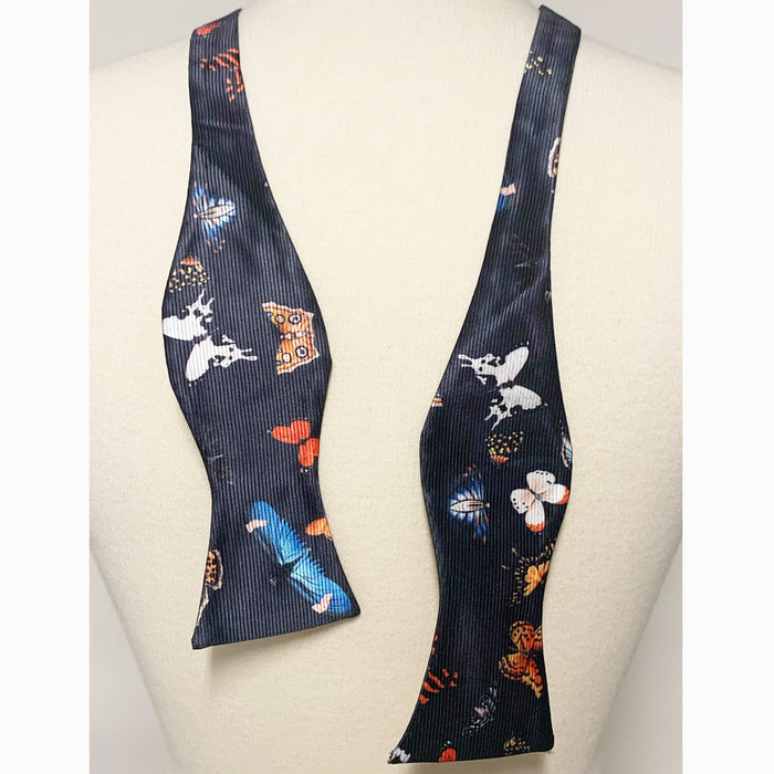 A bow tie with a pattern featuring artistic characters and motifs on a dark background.