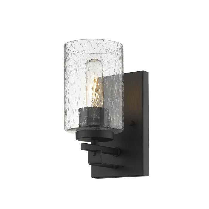 Bottom up right side view of the lighted Bronze metal wall sconce with clear seeded glass shade – modern indoor wall lighting fixture.