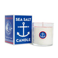 A white candle in a glass container with image of an anchor, next to a box labeled 'Sea Salt Candle'.