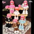 Three-tier wooden stand displaying pink-haired, blue-eyed anime dolls from the Cat Island-Black Cat Or Candy Cat Series Articulated Figure Blind Box, set on a lace doily.