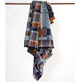 Plaid blanket draped over a wooden rod on a white background