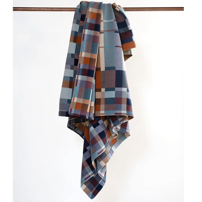Plaid blanket draped over a wooden rod on a white background