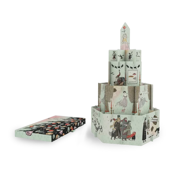 A vintage-style illustrated paper tower set with a matching box placed beside it on a plain white background. The tower is made of multiple printed paper panels with whimsical drawings, and the box shows a matching patterned cover.