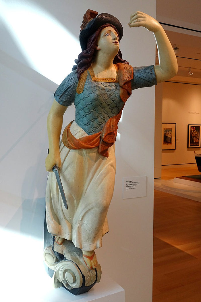 Wood statue of Britannia, a historical figurehead often used on the bowsprit of sailing ships, depicting a woman in period clothing holding a sword.