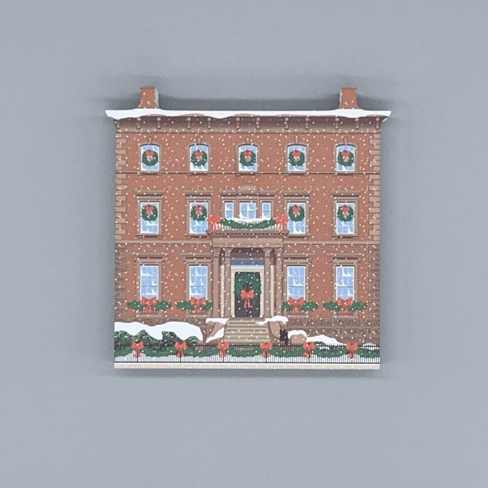 A decorative block featuring the John Tucker Daland House, depicted with holiday decorations.