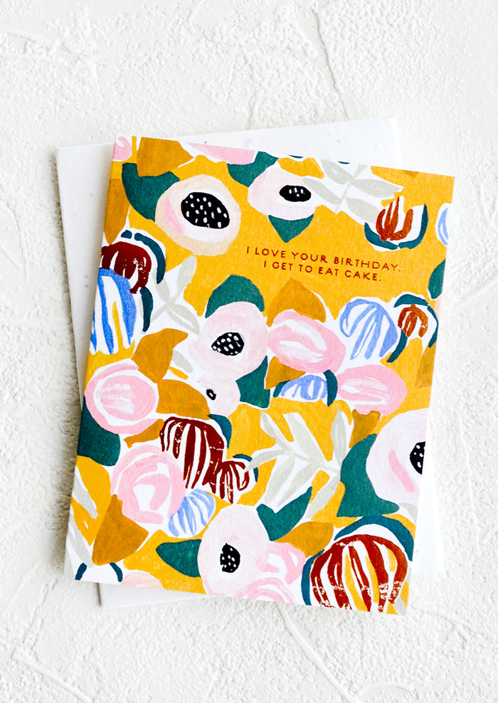 A floral patterned greeting card with yellow background and copper text reading "I love your birthday I get to eat cake".