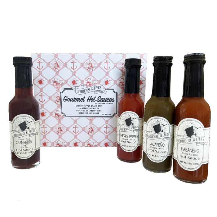 Four bottles of Lighthouse Keepers hot sauce with a decorative box in the background.