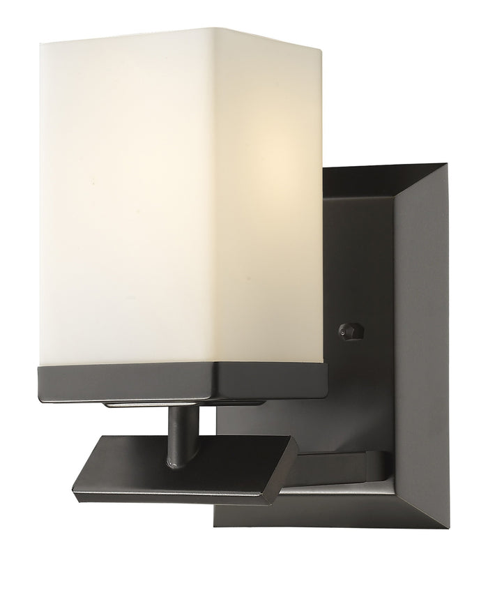 Right side angled view of the lighted One-light bronze wall sconce with cube frosted glass and rectangular backplate