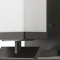Zoomed in view of the arm base and partial shade of the One-light bronze wall sconce with cube frosted glass and rectangular backplate