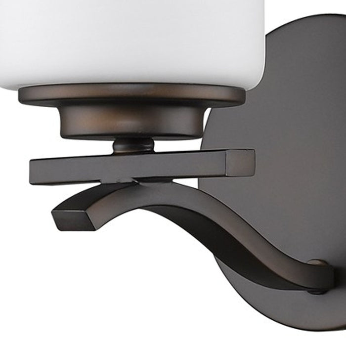 Zoomed in view of the wall plate, arm and shade base of the  One-light bronze wall sconce with frosted cylindrical glass shade and curved metal arm