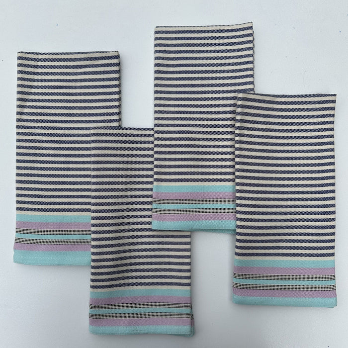 A set of four striped cotton napkins in shades of blue, gray, and beige, handwoven and laid out flat.