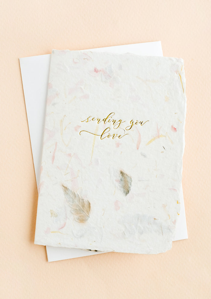 A greeting card made from handmade flower paper with gold script on front that reads "Sending You Love".