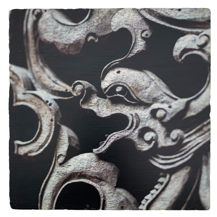 A square trivet with a printed image of a carved Dragon Gate lattice screen in a dark color.