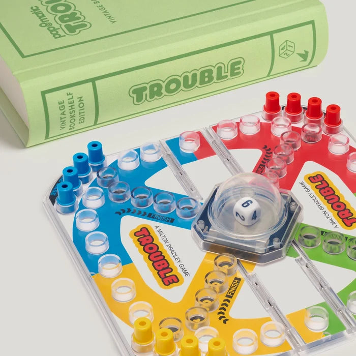 Trouble board game with dice and colorful pegs on a white background