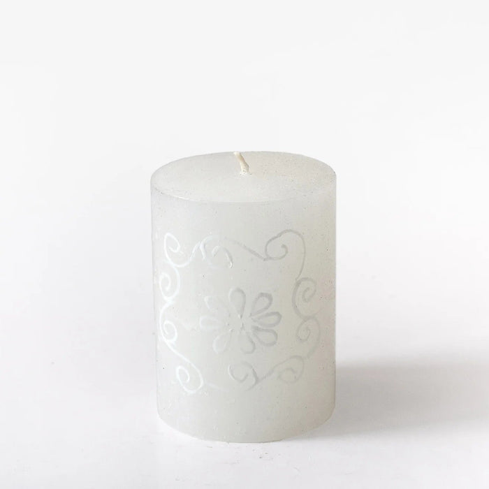 White candle with intricate designs on a white background