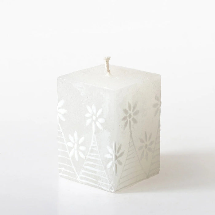 White square candle with floral cutouts on a white background