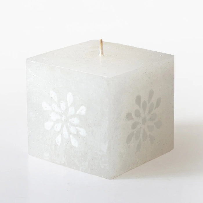 Square white candle with decorative cutout on a white background