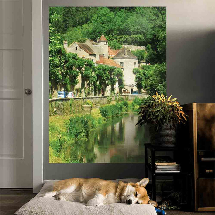 60 inch decal of a stone building in France along a river installed on a wall with dog sleeping on bed in foreground